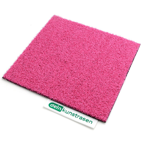 Eine aufgerollte Matte in kräftigem Pink mit einer strukturierten, rutschfesten schwarzen Unterseite liegt auf einer weißen Oberfläche. Die pinke Oberseite wirkt faserig und robust.