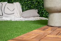 Nahaufnahme einer Ecke eines rechteckigen, grünen Kunstrasenstücks auf weißem Hintergrund.